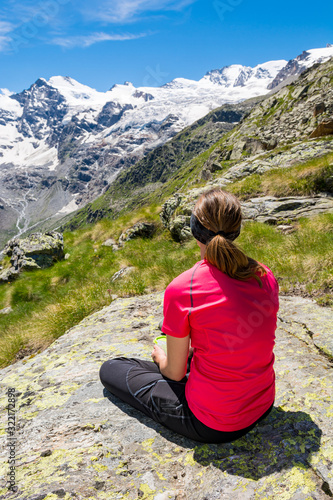 Rear view of attractive brunette meditating in picturesque mountains.