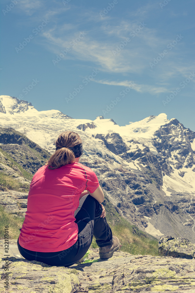 Rear view of attractive brunette meditating in picturesque mountains.