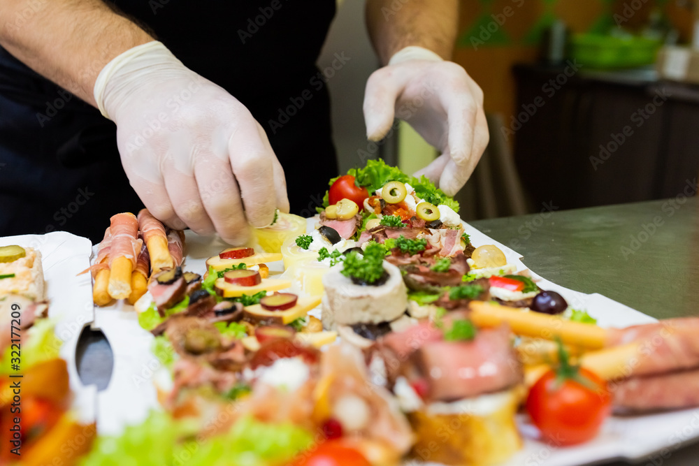 Chef preparing fresh finger food on paper plate for delivery.