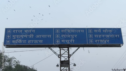 Indian road sign board in which different locations directions is written- Raj Bhavan, Sachiwalaya, Survey Chawk, CM residence,Rajpur, Sahastradhara, Circuit House, Mussoorie, raipur. Flying crows photo