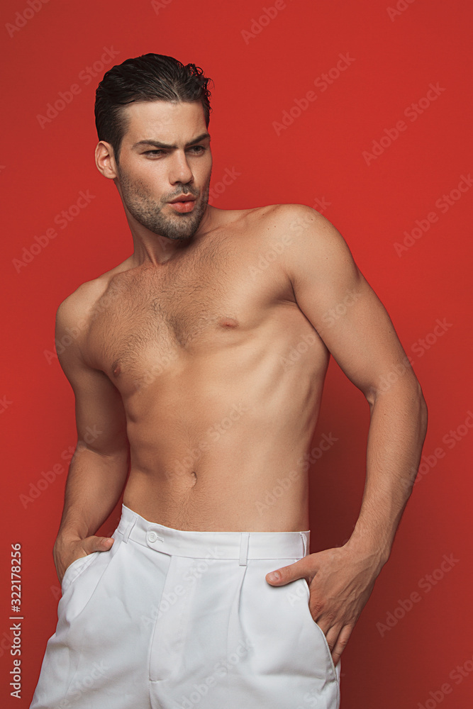 Muscle strong beautiful stripped male model in white casual suit on red isolated font background 