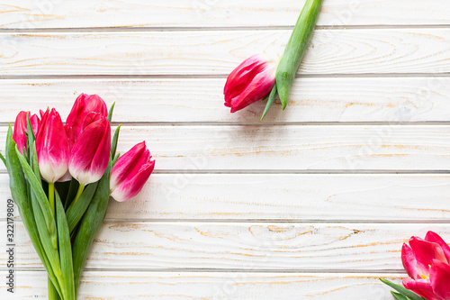 Beautiful pink tulips on white wooden background with copy space for your text. Greeting card template. Spring holidays concept.