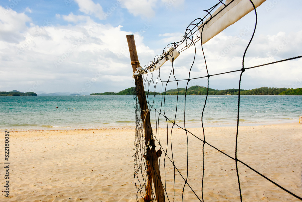  Beach volleyball net on the empty beach with the blue sea and sky.