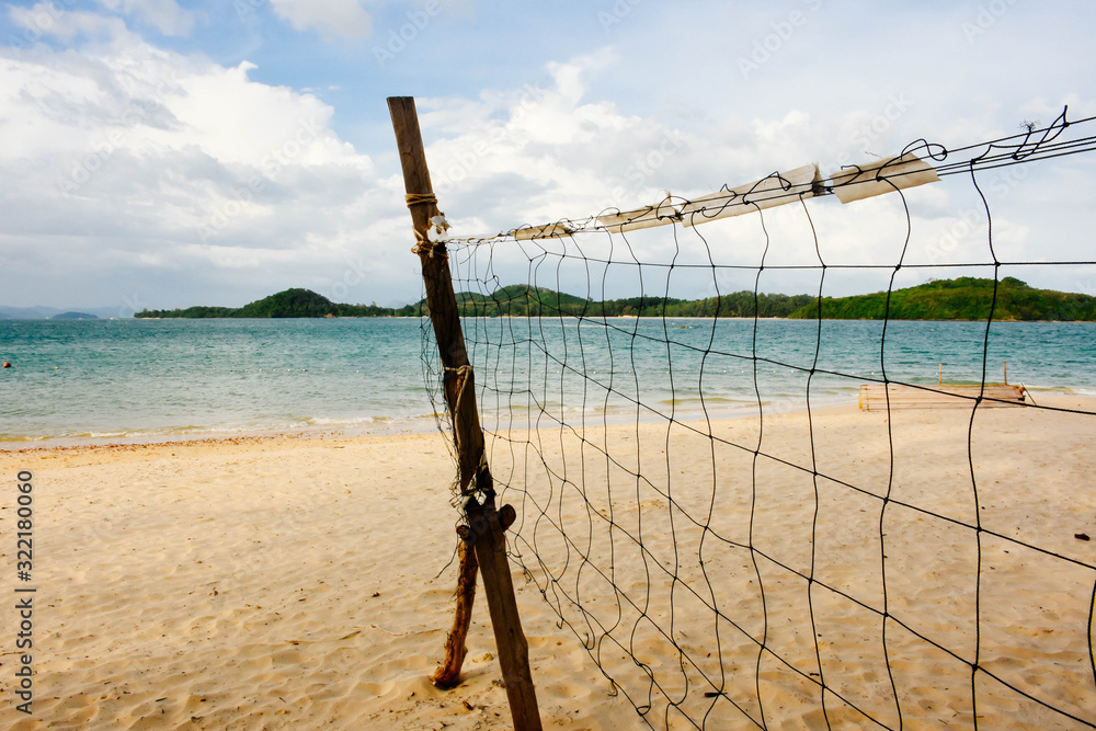  Beach volleyball net on the empty beach with the blue sea and sky.