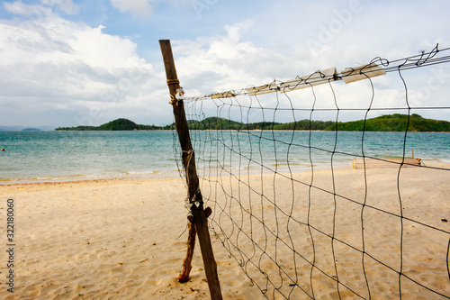  Beach volleyball net on the empty beach with the blue sea and sky.