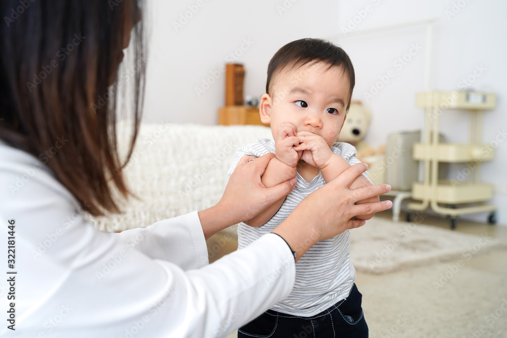Asian innocent baby boy sucking his own thumb and finger in living room at home. Mom is trying to stop him. Asian innocent baby boy sucking his own thumb and finger in living room at home. Mom is trying to stop him.