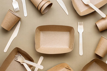 Brown kraft paper food containers, forks and knifes on beige background