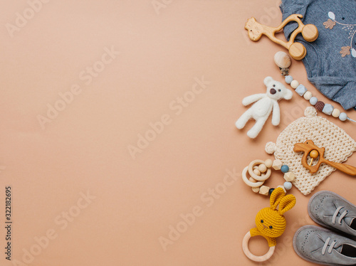 Newborn baby wooden toys, clothes and shoes on beige background