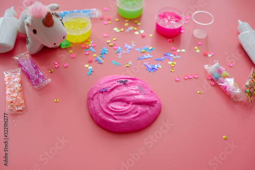 a girl making slime herself. child making slime on pink background. © klavdiyav