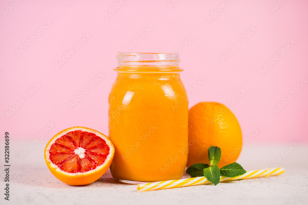 Close up is a jar of fresh yellow smoothie made from natural fruit on a pink background. Close up is a jar of fresh yellow smoothie made from natural fruit on a pink background.