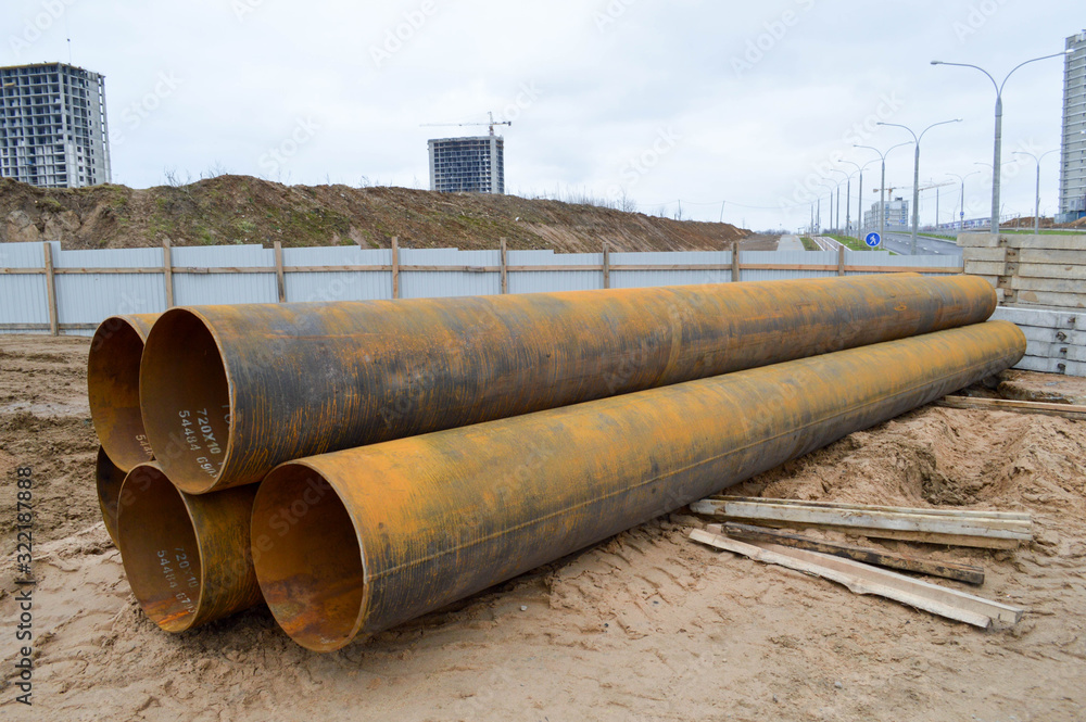 Large iron metal sewer plumbing pipes of large diameter for the industrial construction of water supply or sewage at a construction site during the repair Large iron metal sewer plumbing pipes of large diameter for the industrial construction of water supply or sewage at a construction site during the repair