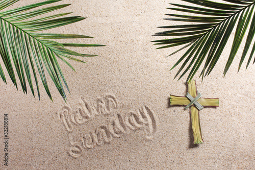 Cross and Palm Tree Leaves on sand. Palm sunday concept. Top view