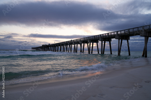 Scenic View of Pier at Panama City Beach FL with Crashing Green Waves and Blue Clouds 