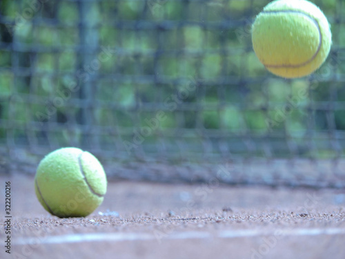 Pelota de tenis en movimiento con fondo natural acompañado con una raqueta en cancha de tenis