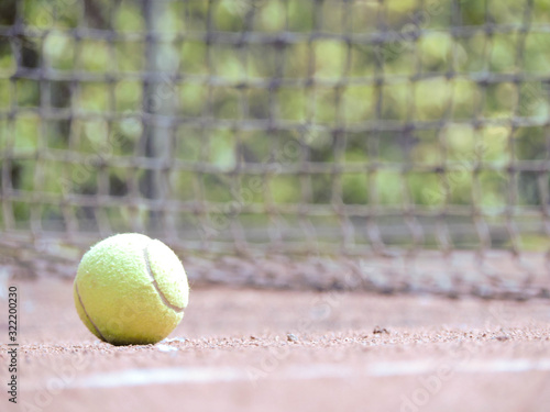 Pelota de tenis en movimiento con fondo natural acompañado con una raqueta en cancha de tenis