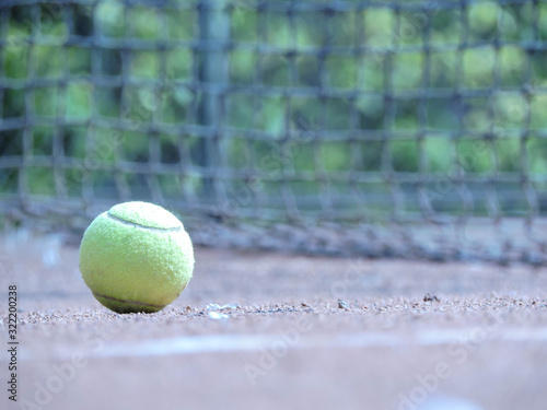 Pelota de tenis en movimiento con fondo natural acompañado con una raqueta en cancha de tenis