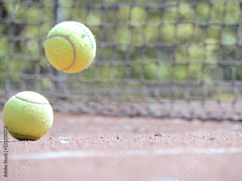 Pelota de tenis en movimiento con fondo natural acompañado con una raqueta en cancha de tenis