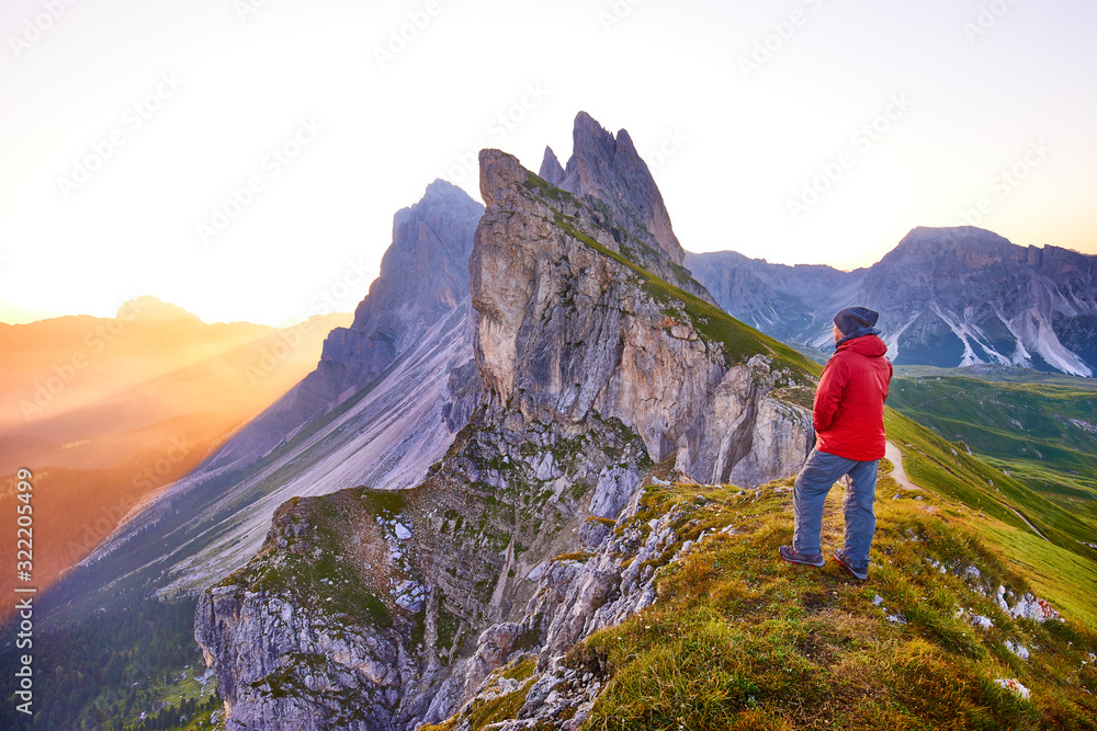 Amazing view on Seceda peak. Trentino Alto Adige, Dolomites Alps, South Tyrol, Italy, Europe. Odle mountain range, Val Gardena. Majestic Furchetta peak in morning sunlight. Man traveler traveling