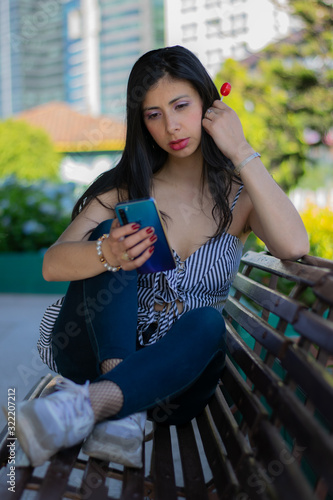 Colombian woman checks her cell phone sitting in a wooden chair