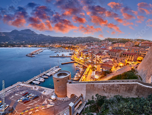 View from the walls of the citadel of Calvi on the old town with historic buildings at evening sunset. Bay with yachts and boats. Luxurious marina and popular tourist destination. Corsica, France photo