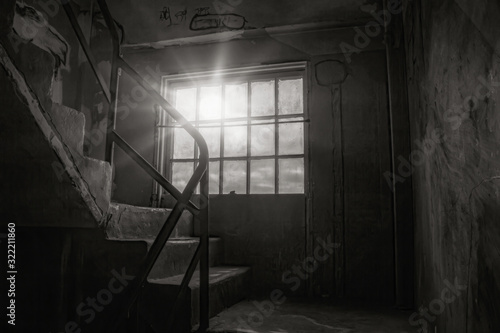 Grungy stairwell in abandoned building, steel frame window panes with sun streaming through, stairs, railings, graffitti, nobody