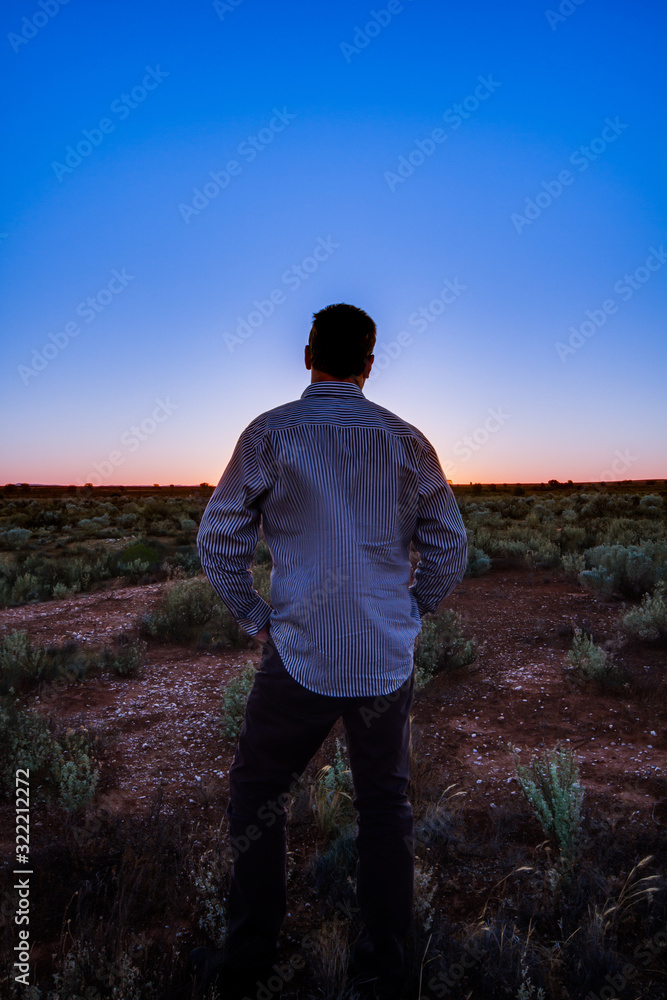 Man Standing in a Field Looking at the Sunset