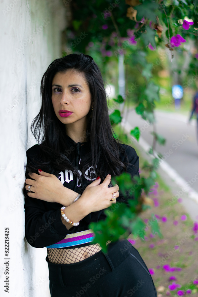 Fototapeta premium pretty Colombian woman lying on a white wall in a garden
