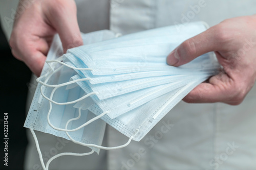 Doctor infectiologist is holding medical masks, precautions for viral infections transmitted by airborne droplets photo