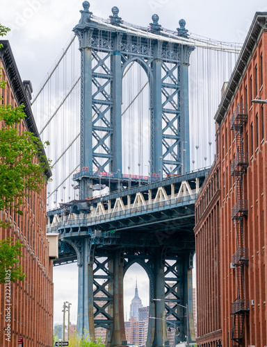 View of the famous Manhattan Bridge, with the Empire State Building in the background, located in the neighborhood of Brooklyn, New York, USA