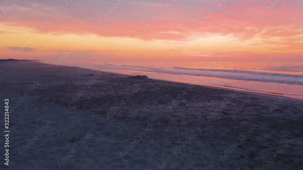 Low aerial, lifeguard tower on empty beach with dramatic purple cloudy sunset Low aerial, lifeguard tower on empty beach with dramatic purple cloudy sunset