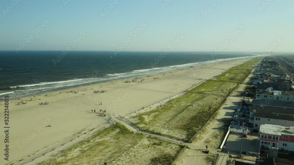 Aerial, many people on large beach next to beach houses and beachside suburb Aerial, many people on large beach next to beach houses and beachside suburb