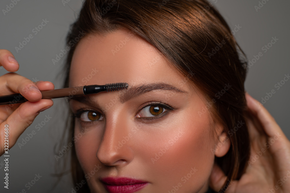 Beautiful eyes of woman with amazing make up. Girl is applying makeup on eyebrows