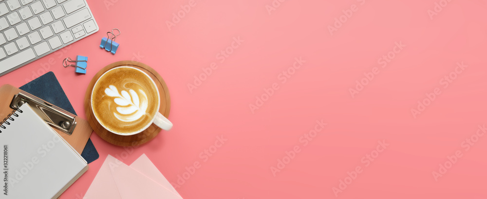 Flat lay, top view office table desk. Workspace with blank clip board, keyboard, office supplies, pencil, green leaf, and coffee cup on pink background