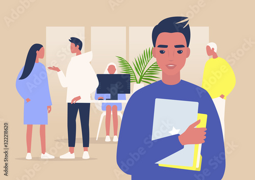 A portrait of a young male manager holding a laptop and folders, a group of coworkers on background, daily office life