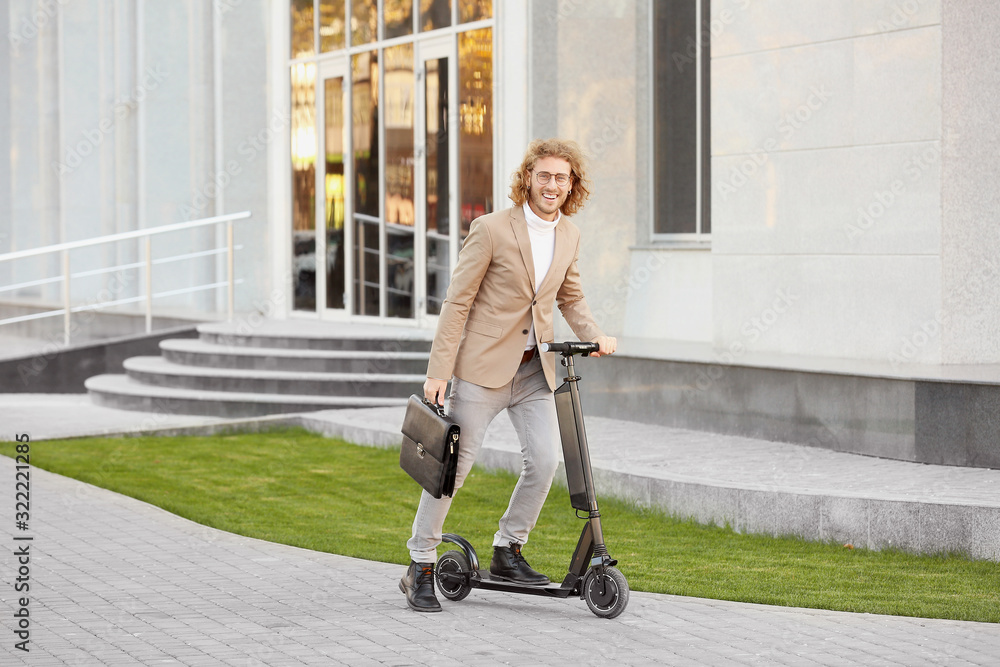 Young businessman with kick scooter outdoors Young businessman with kick scooter outdoors