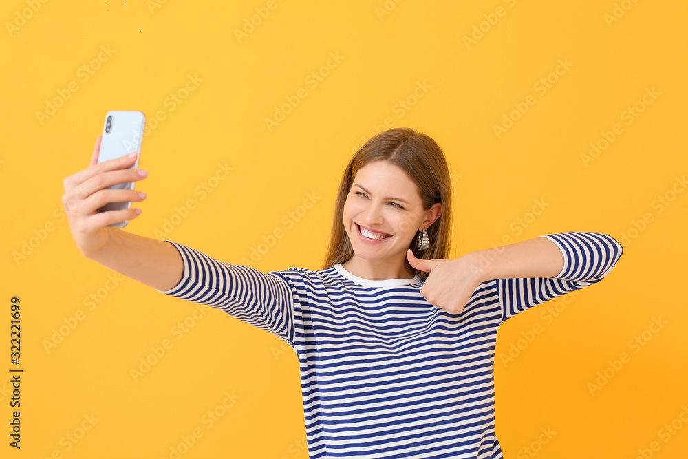 Beautiful young woman taking selfie on color background Beautiful young woman taking selfie on color background