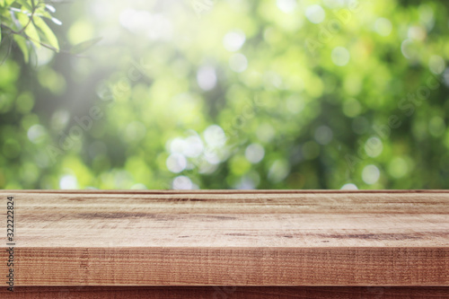 Wooden table and blurred fresh garden nature bokeh background.