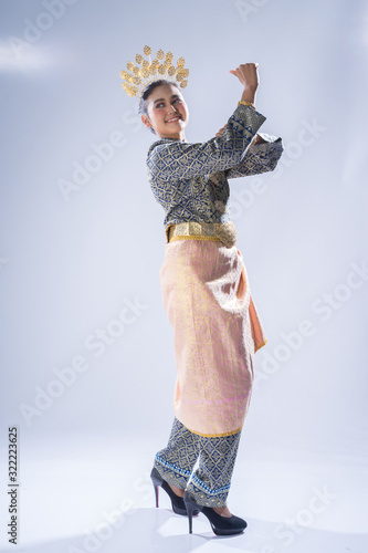 A beautiful Malaysian traditional female dancer performing a cultural dance routine in a traditional outfit on a stage. Full length portrait. photo