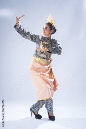 A beautiful Malaysian traditional female dancer performing a cultural dance routine in a traditional outfit on a stage. Full length portrait.
