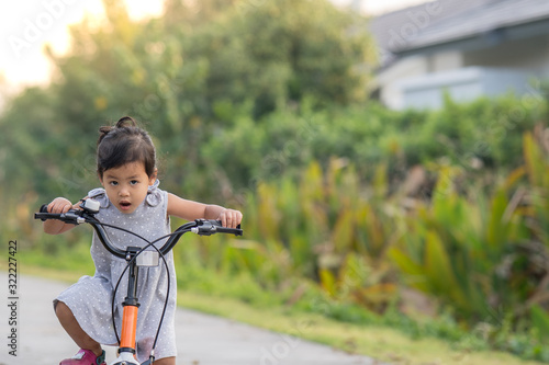 Cute Little Girl Riding Her Orange Bike in the Park 