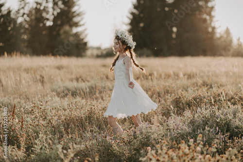 Canvas Print happy joyful young girl in a white dress and with a flower wreath on her head in