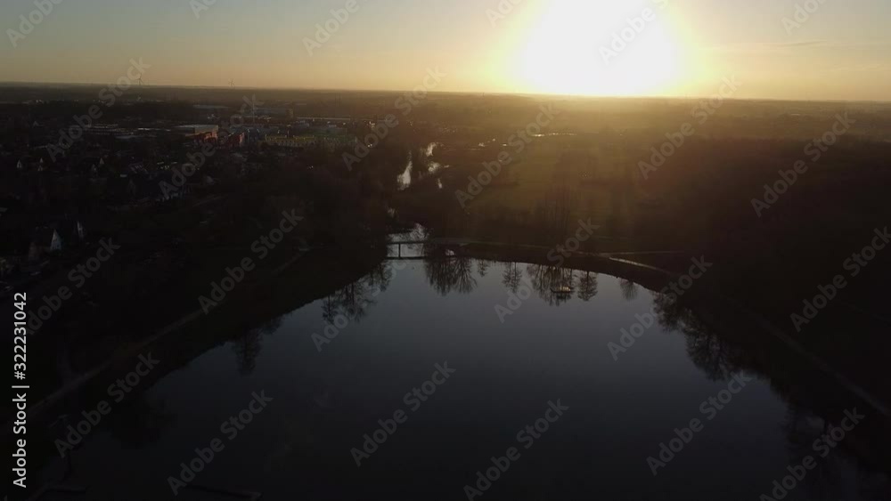 Aerial flight above lake with tree reflection in water during sunset in background Aerial flight above lake with tree reflection in water during sunset in background
