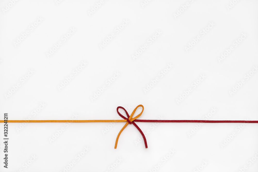 Yellow and red ribbon isolated on white background. two colors chamois string tied in a bow.