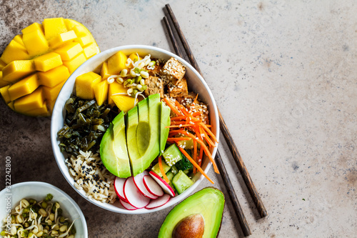 Vegan poke bowl with avocado, tofu, rice, seaweed, carrots and mango, top view. Vegan food concept. photo