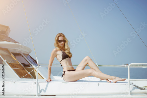 Beautiful young woman in a bikini relaxes and sunbathes aboard a white sea yacht