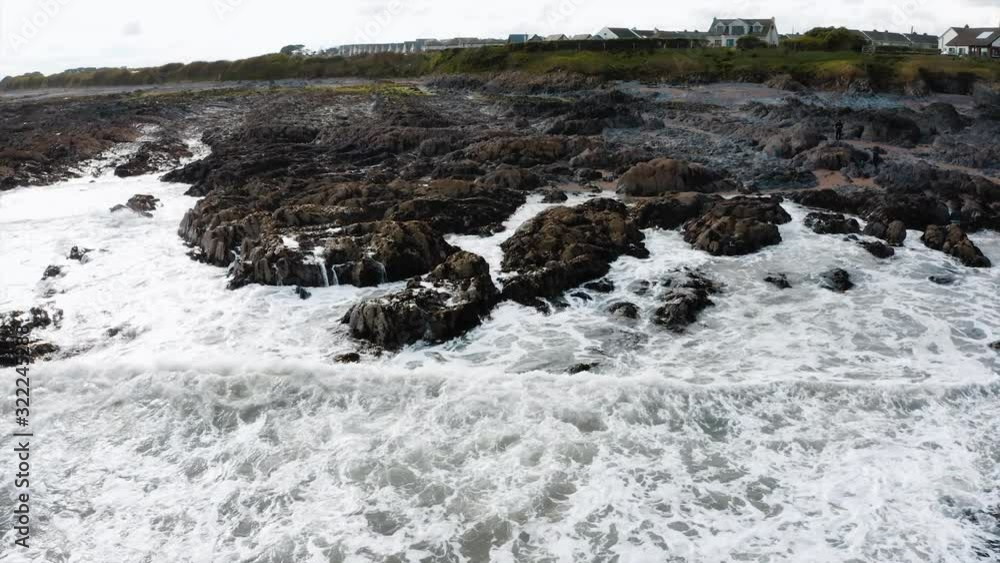 The rocky beach in Skerries, Ireland. The view of strong waves crashing into the rocky shore. The rocky beach in Skerries, Ireland. The view of strong waves crashing into the rocky shore.
