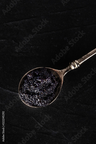 Black caviar on a silver spoon close-up, shot from above on a dark background with a place for text