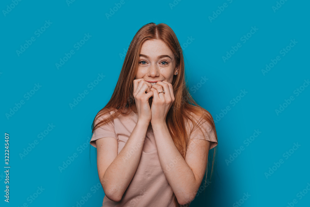 A photo of a beautiful teenager that shows her impatience for something posing in a nice shirt on a blue background A photo of a beautiful teenager that shows her impatience for something posing in a nice shirt on a blue background