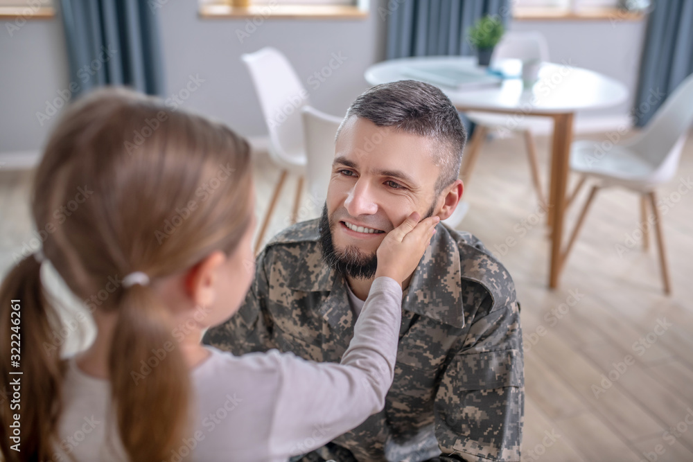 Obraz premium Dad in camouflage looking at little daughter.