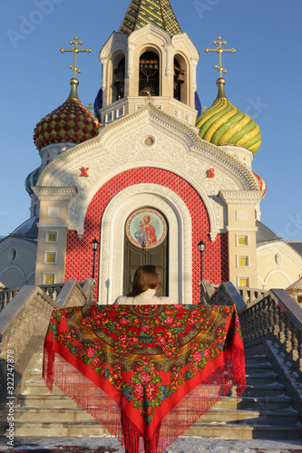 Russian tourist girl in vintage Pavlovo Posad shawl, look. Orthodox Saint Igor Chernigovsky's church in Novo-Peredelkino, Moscow city, Russia. Russian traditional national folk, retro style in fashion photo